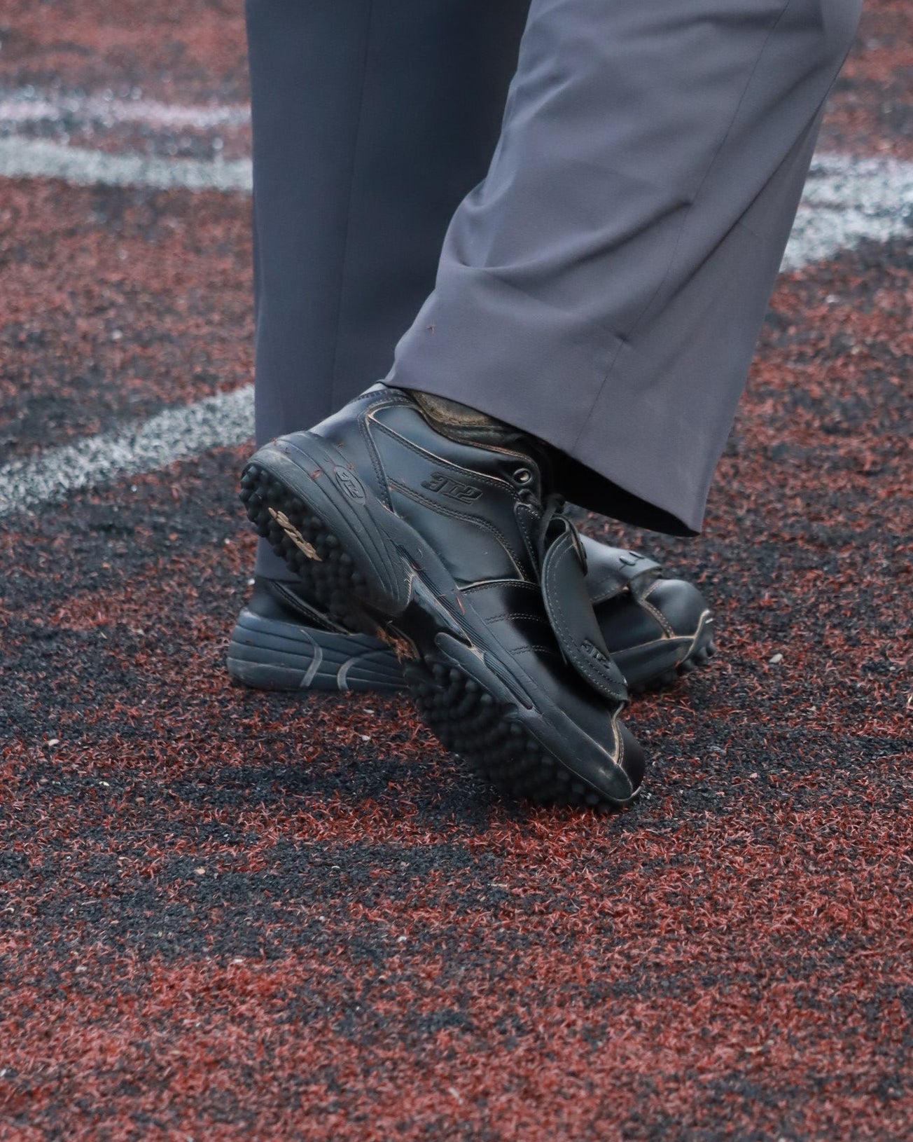 Person wearing black shoes and gray pants standing on a red and green surface